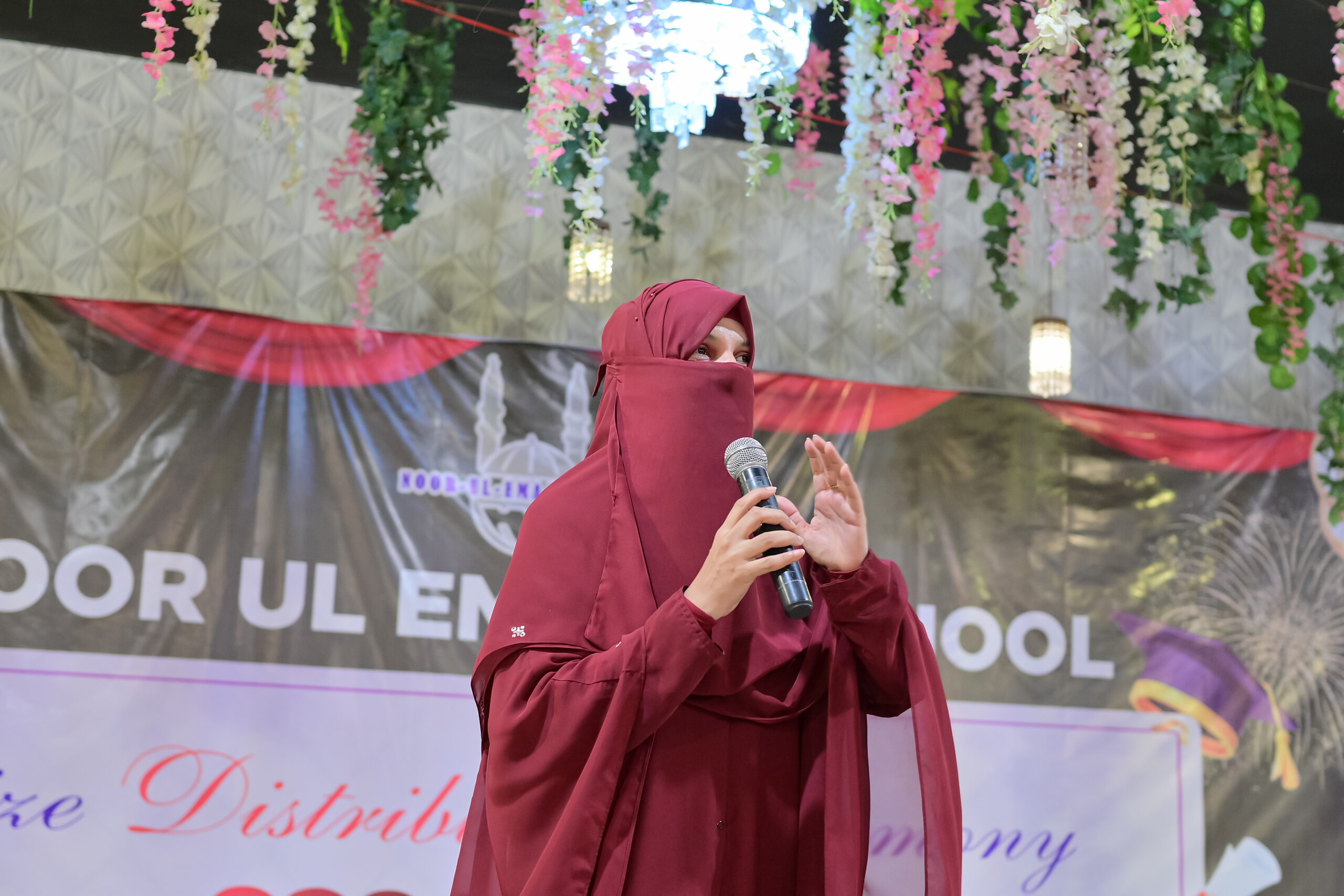 A Noor-ul-Emaan School student speaking confidently on stage during the annual ceremony